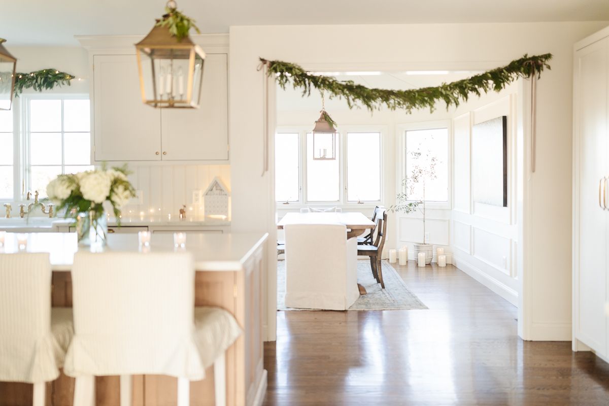 A fresh greenery garland over the entry into a white dining room.