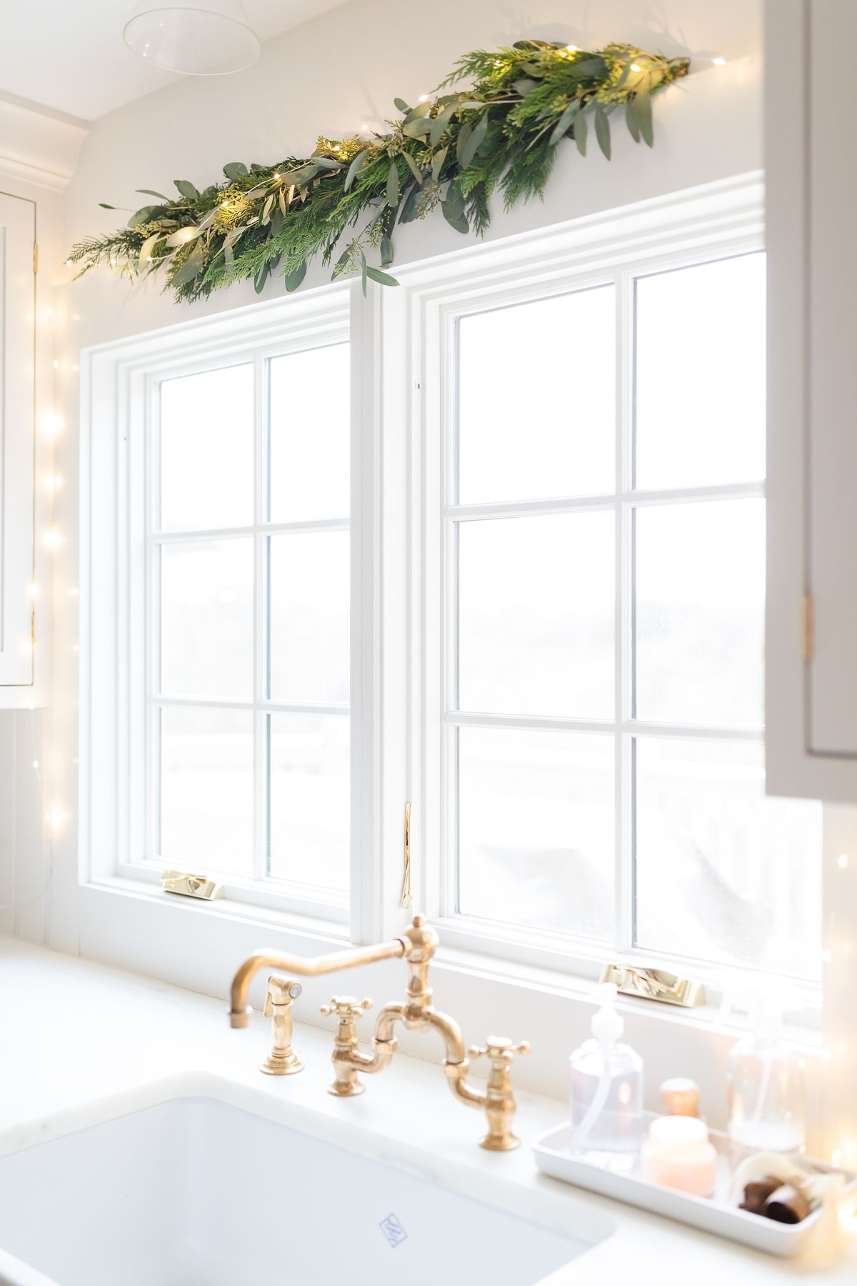 Fresh Christmas greens and lights over a kitchen window