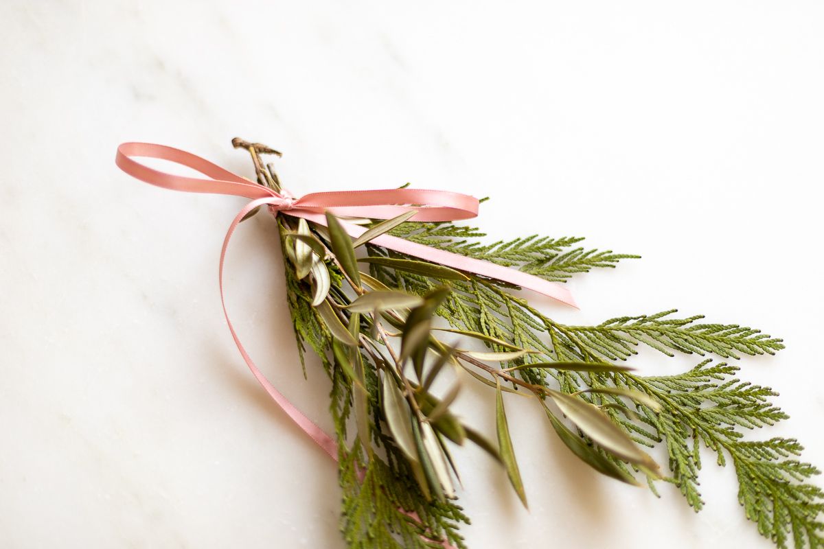 Christmas greenery tied with a pink bow on a marble table top.