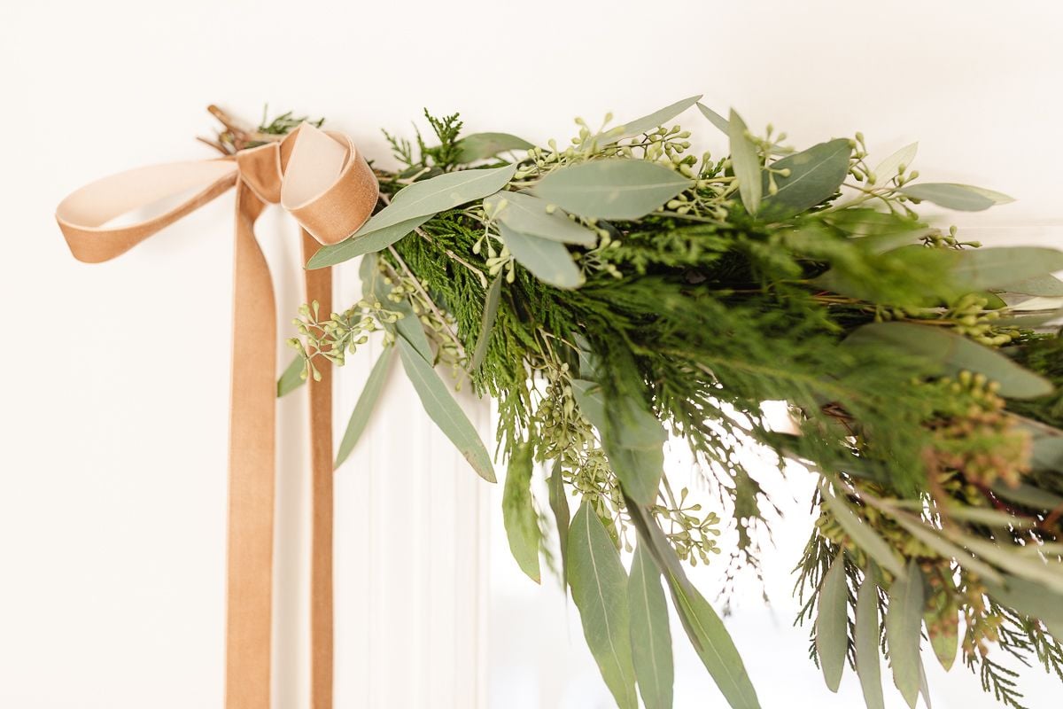 Fresh Christmas greenery tied onto a door frame with a ribbon.