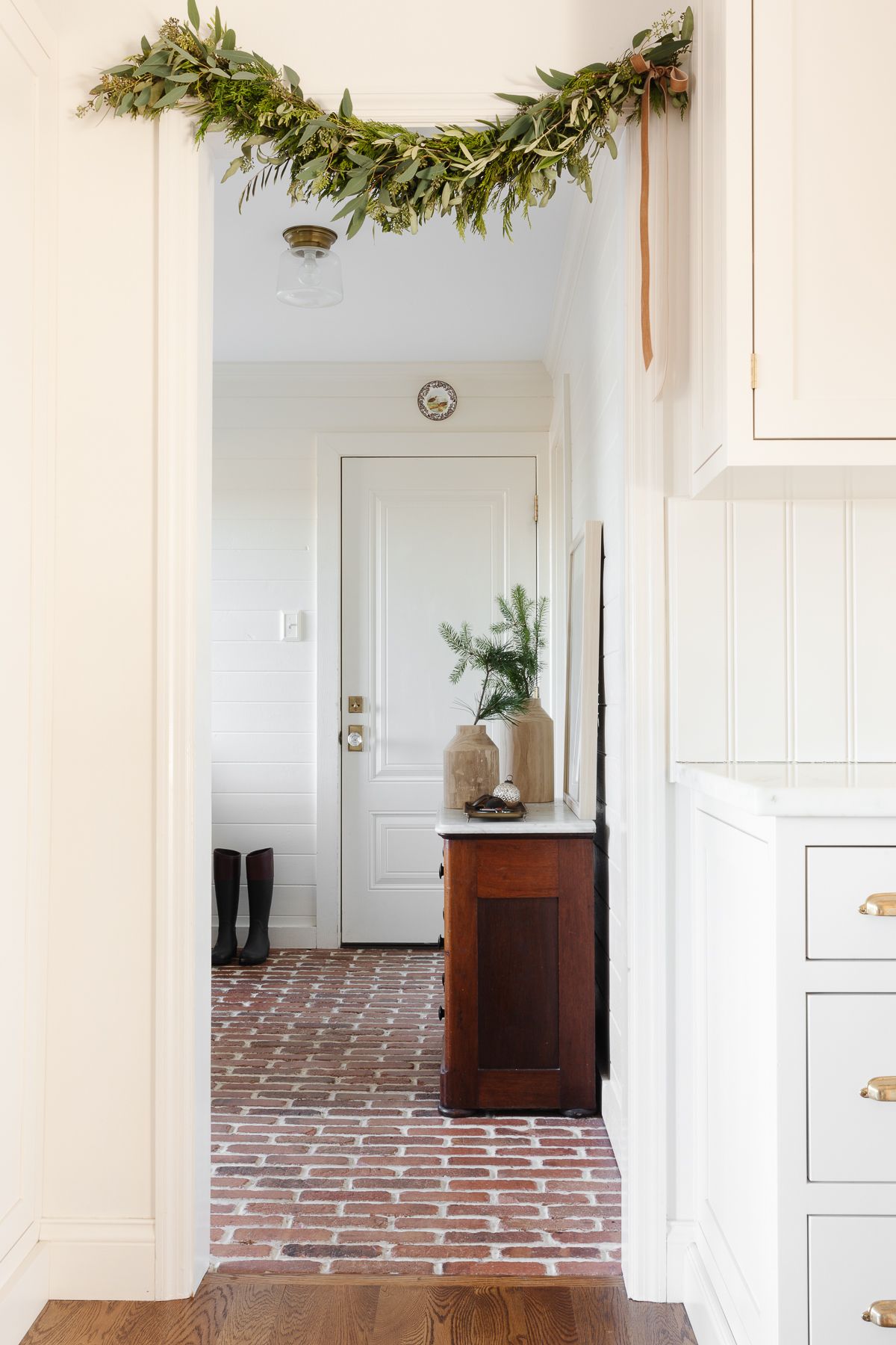 Fresh Christmas greenery garland over an entryway in a cream kitchen.
