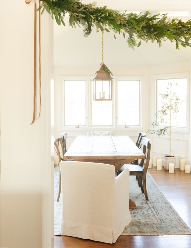 A fresh greenery garland over the entry into a white dining room.