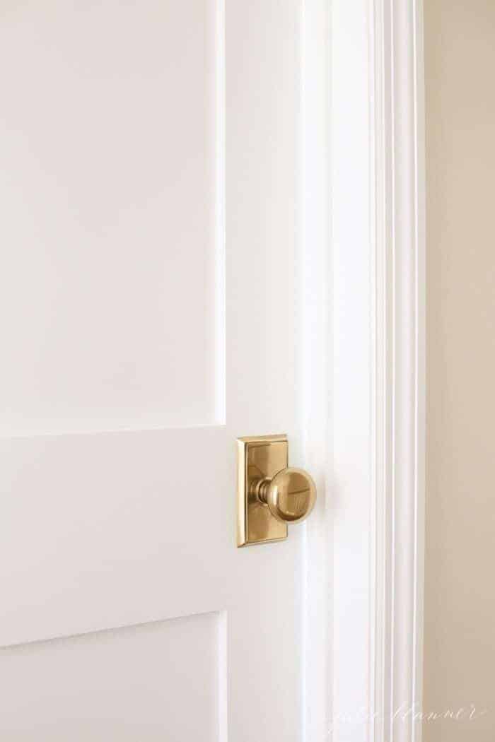 A white wooden door with a classic brass door knob.