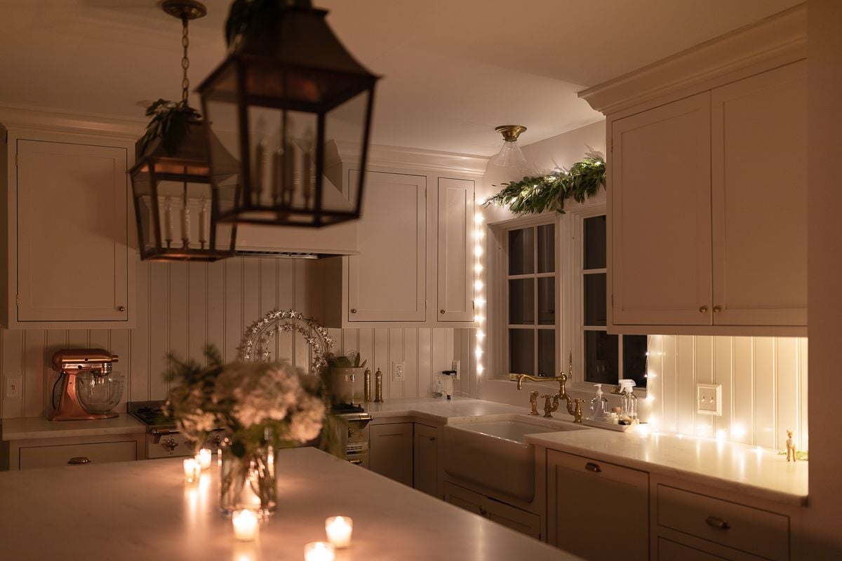 A white kitchen with Christmas flowers and candles on the island at night
