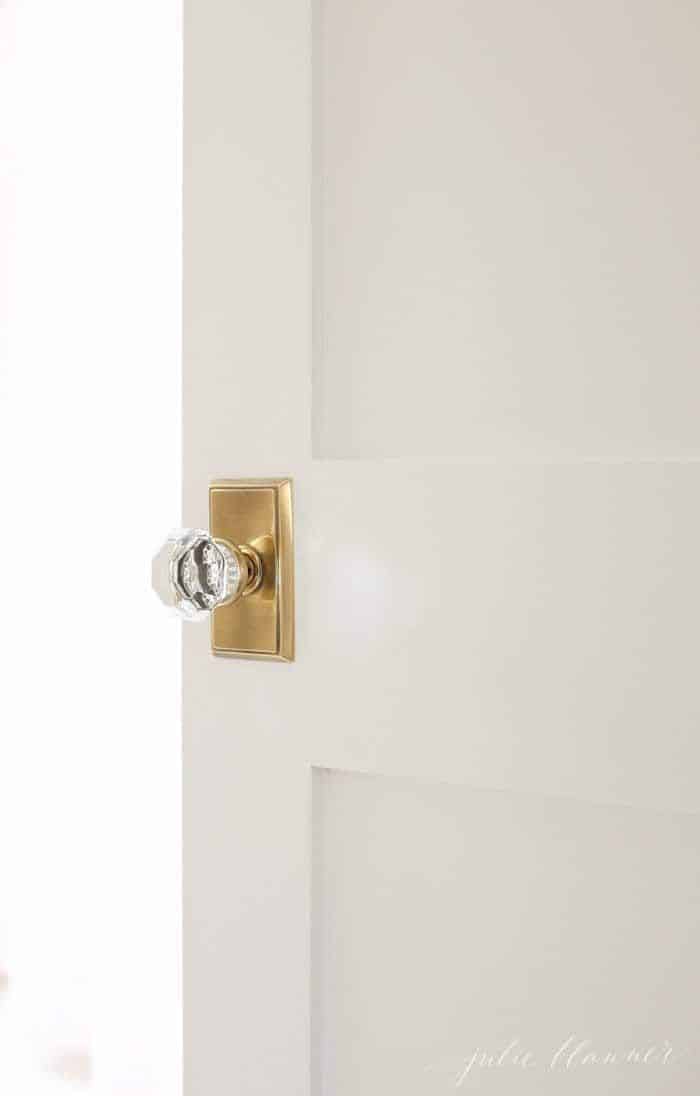 A white wooden door with a classic brass and glass door knob.