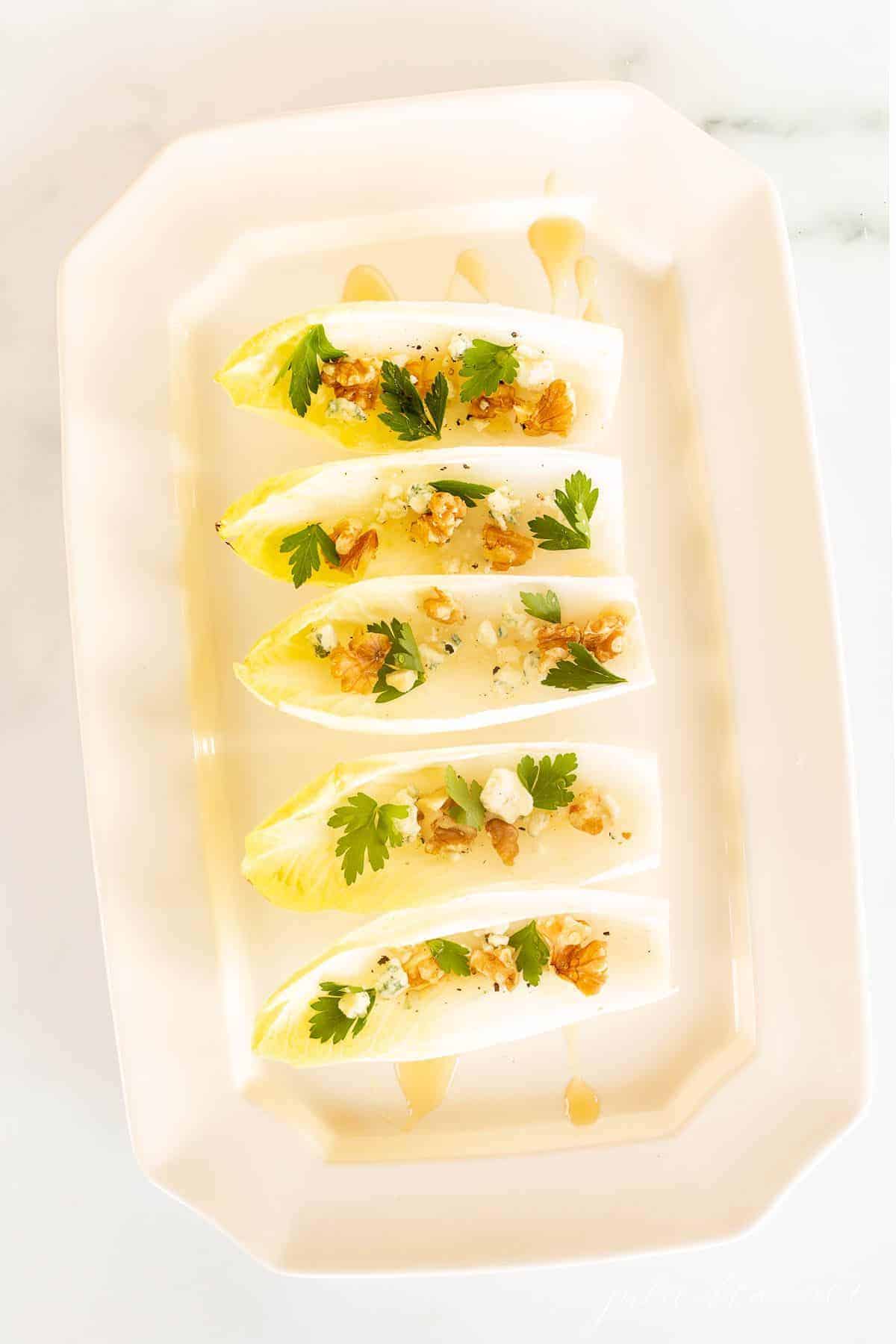 Endive salad on a white platter for a healthy steak side