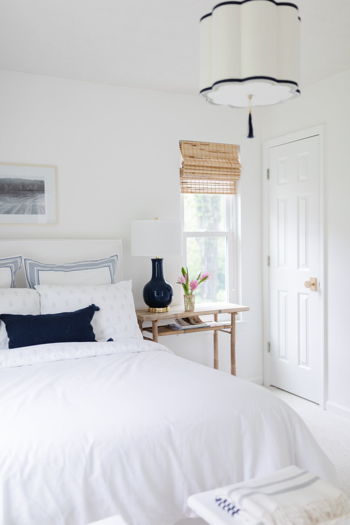 A guest room with white walls and bedding and rattan accents.