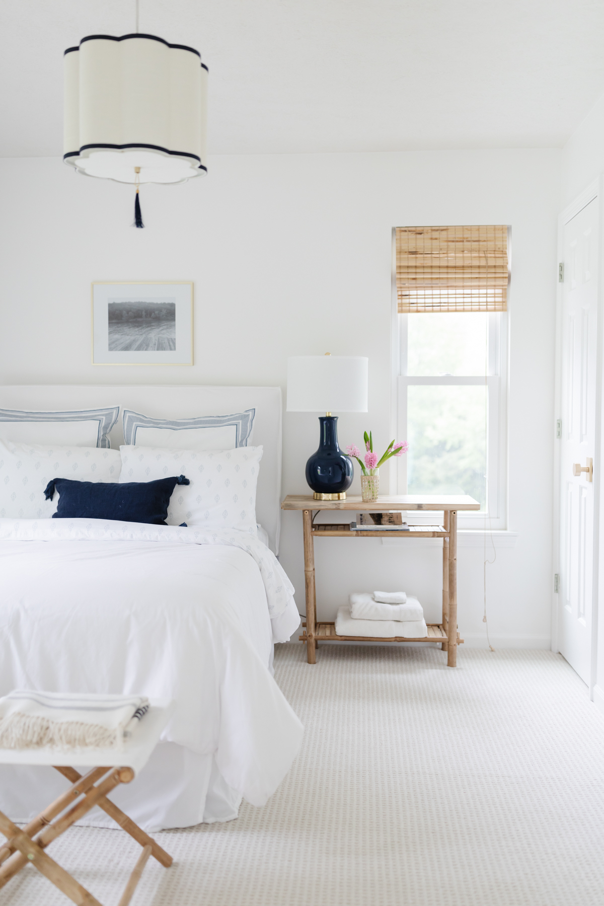 A guest room with white walls and bedding and rattan accents.