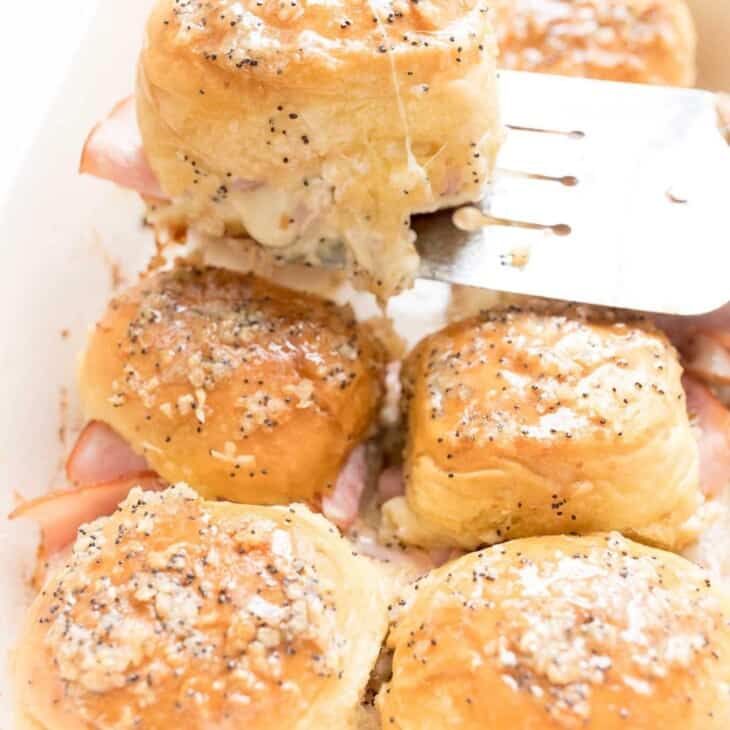 ham and cheese slider on spatula being removed from casserole dish