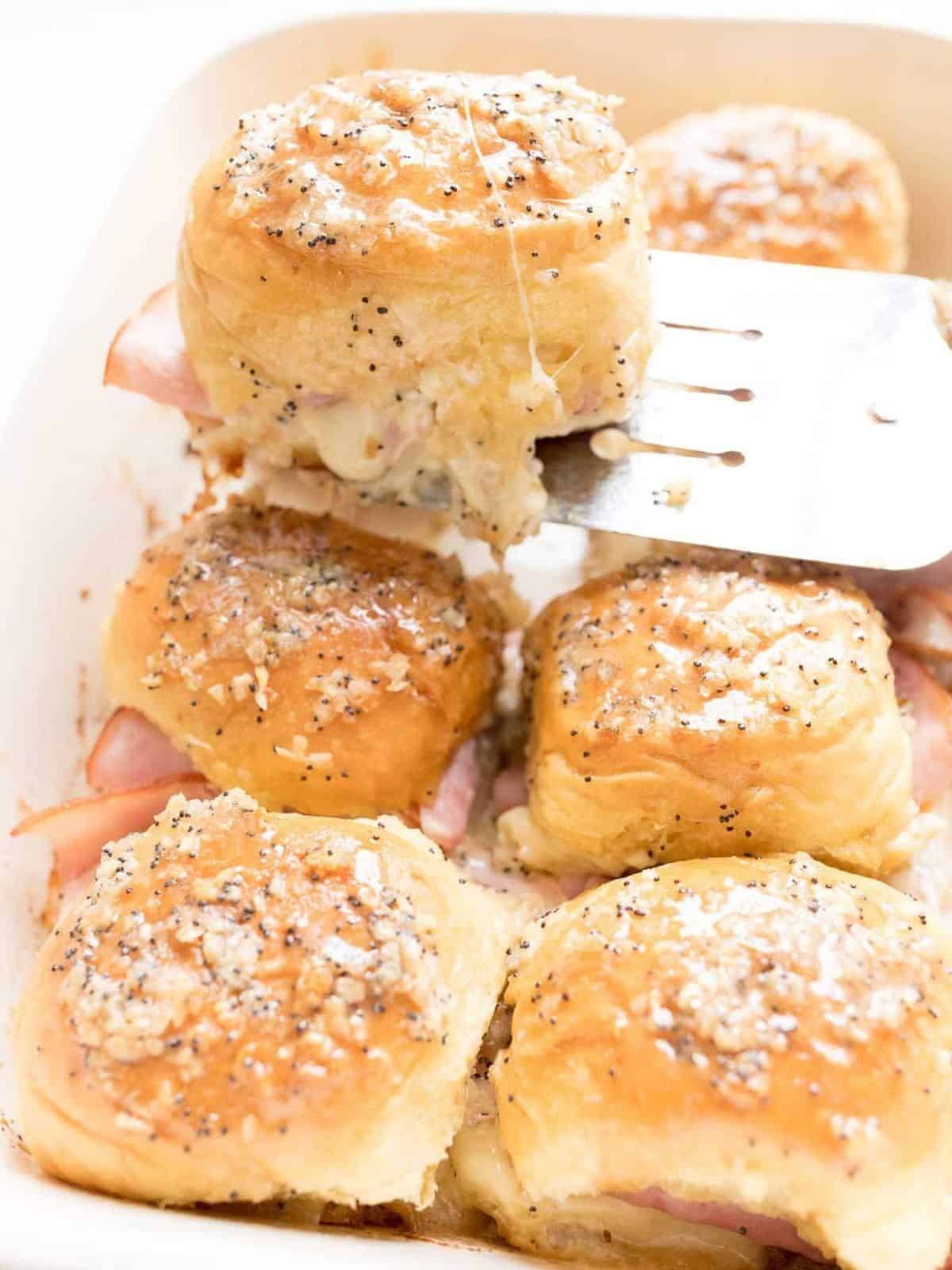ham and cheese slider on spatula being removed from casserole dish