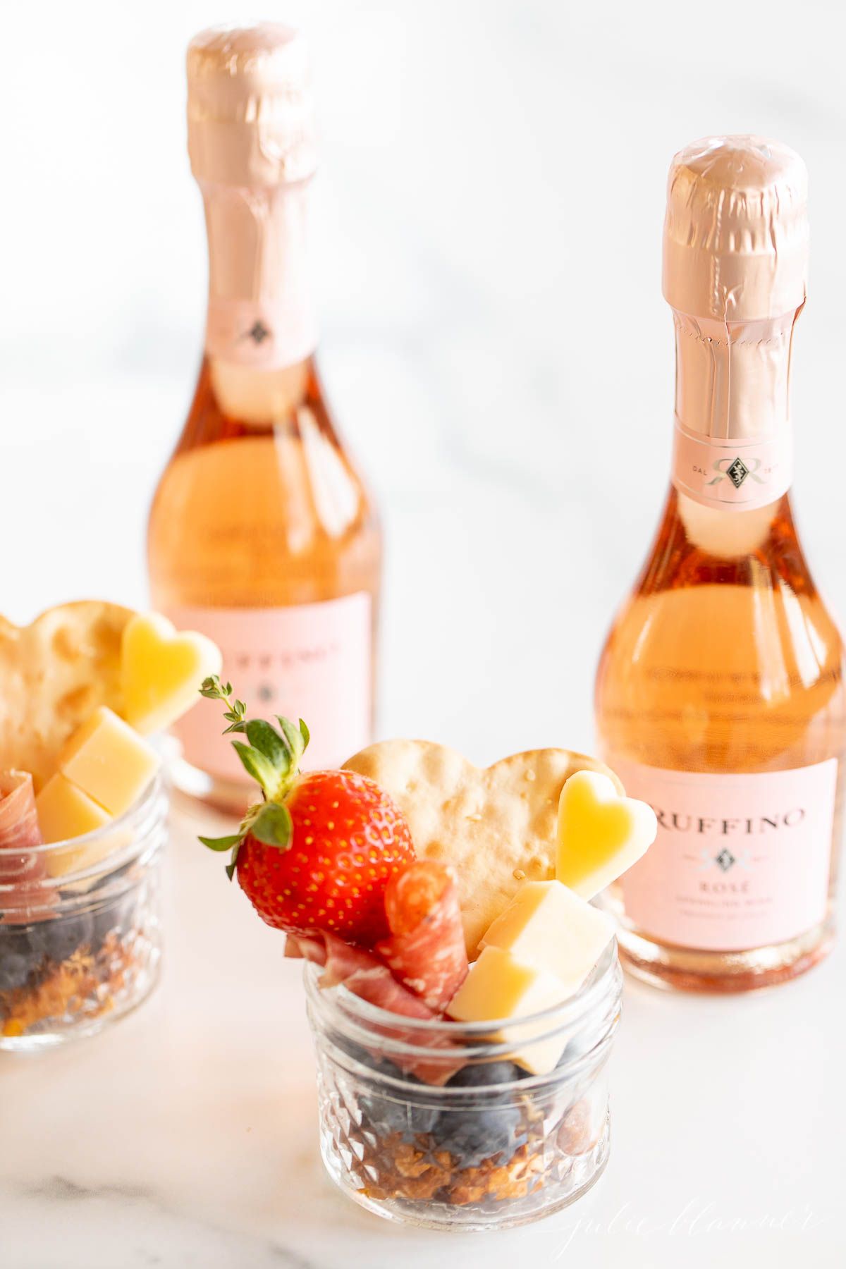 Charcuterie in a jar on a marble countertop, champagne in the background