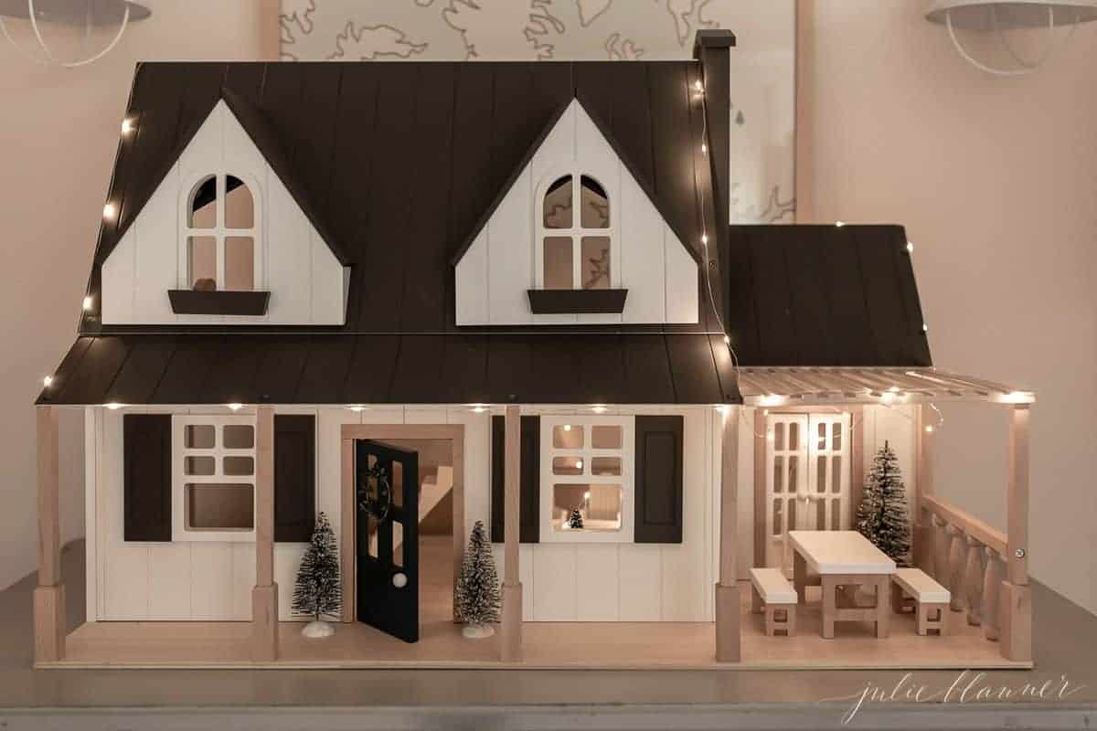 An up close look at a farmhouse dollhouse decorated with indoor Christmas lights ideas.