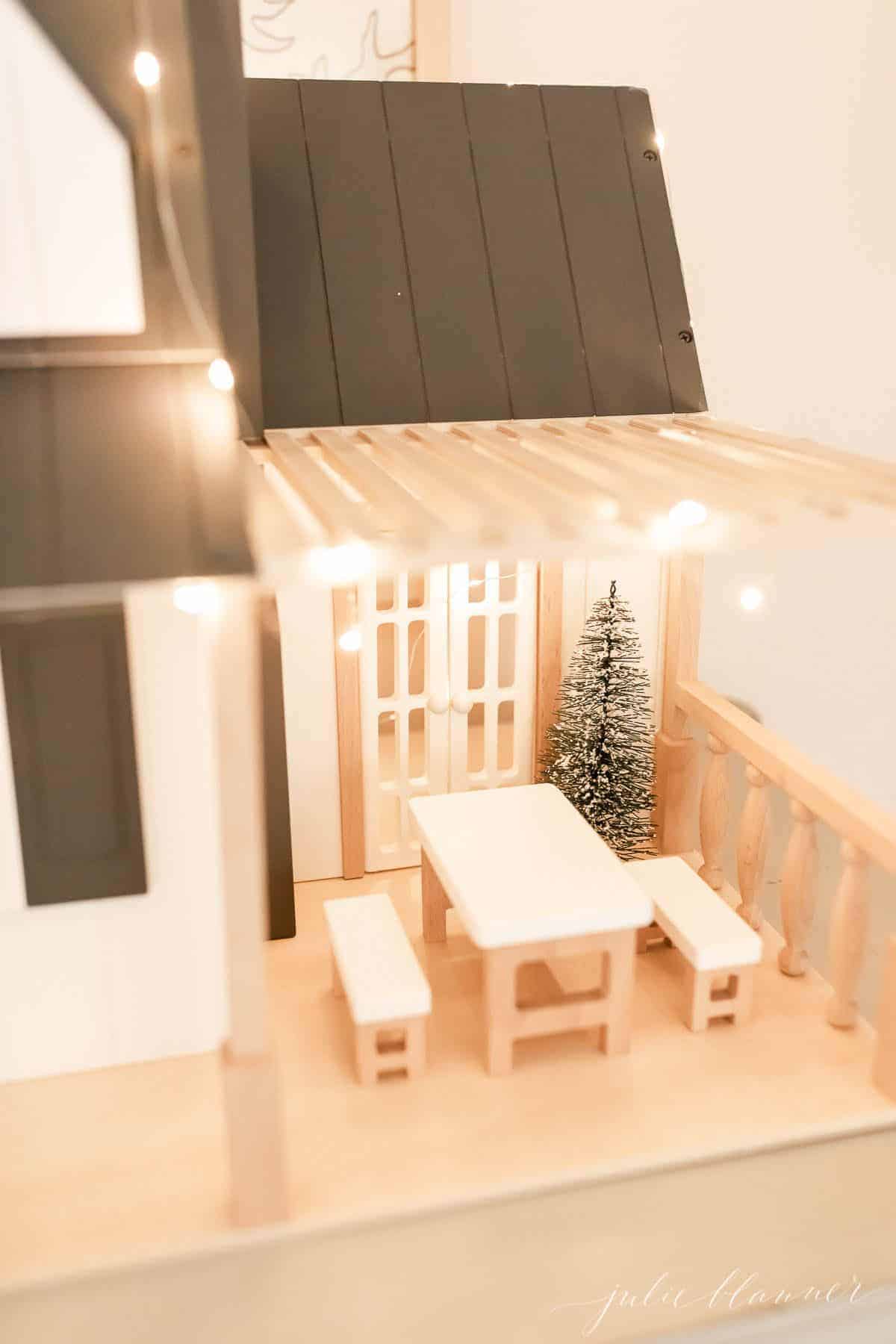 An up close look at a farmhouse dollhouse decorated with indoor Christmas lights ideas.