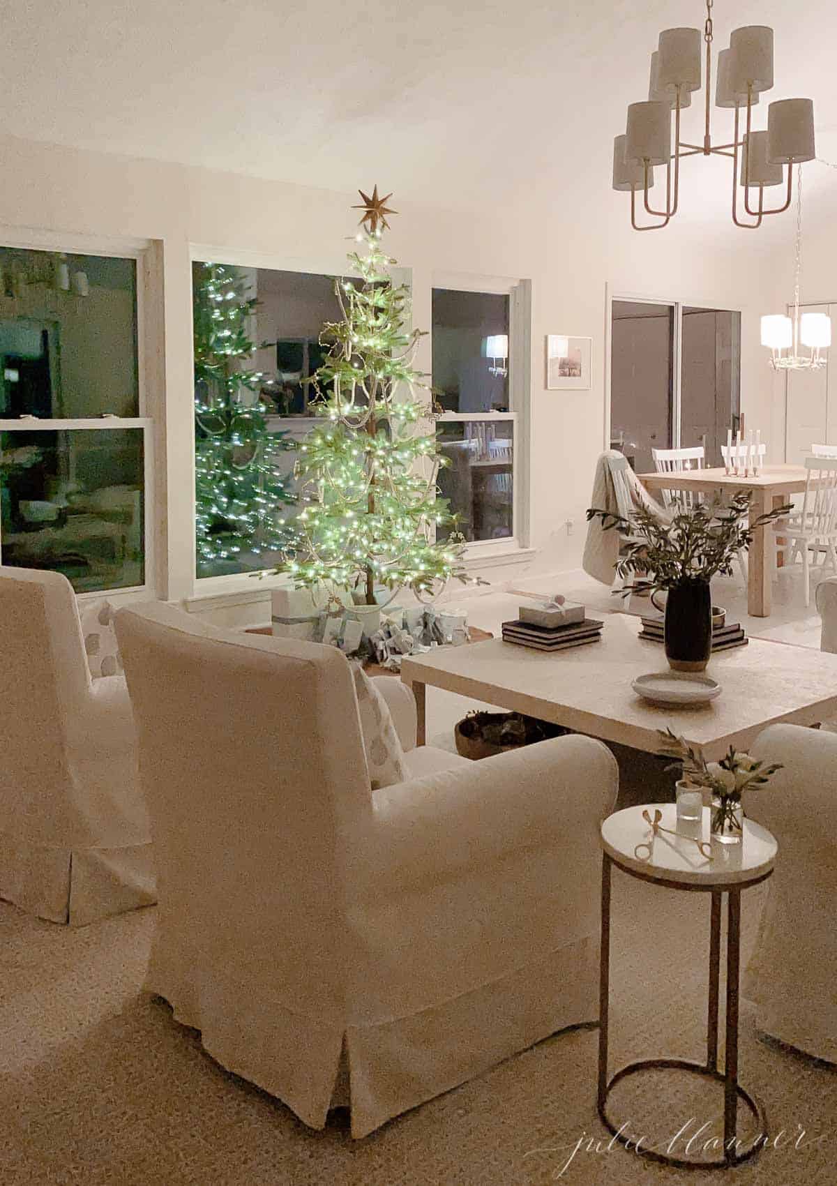 A white living room with a sparsely decorated Scandinavian Christmas tree.