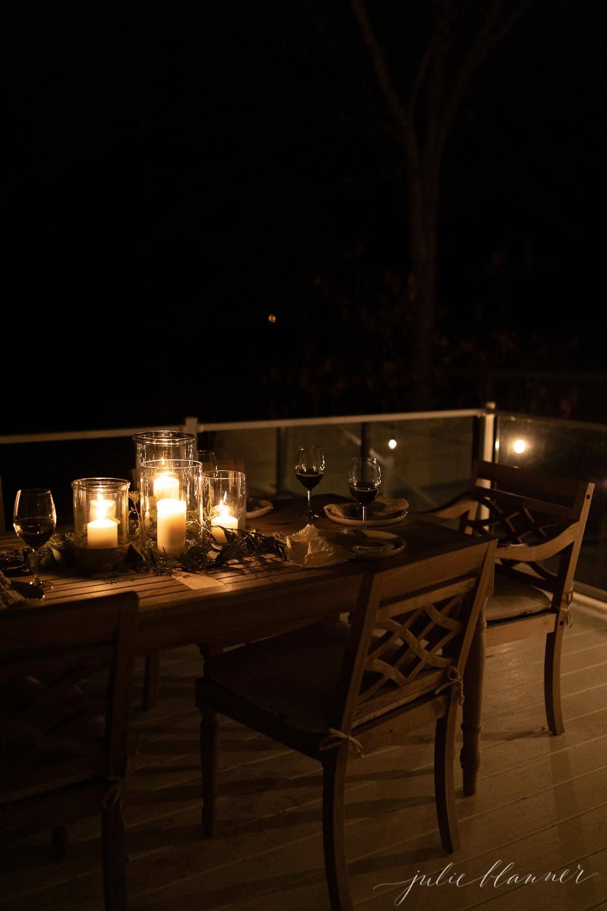 An outdoor dining table with a glowing candle centerpiece for Christmas.