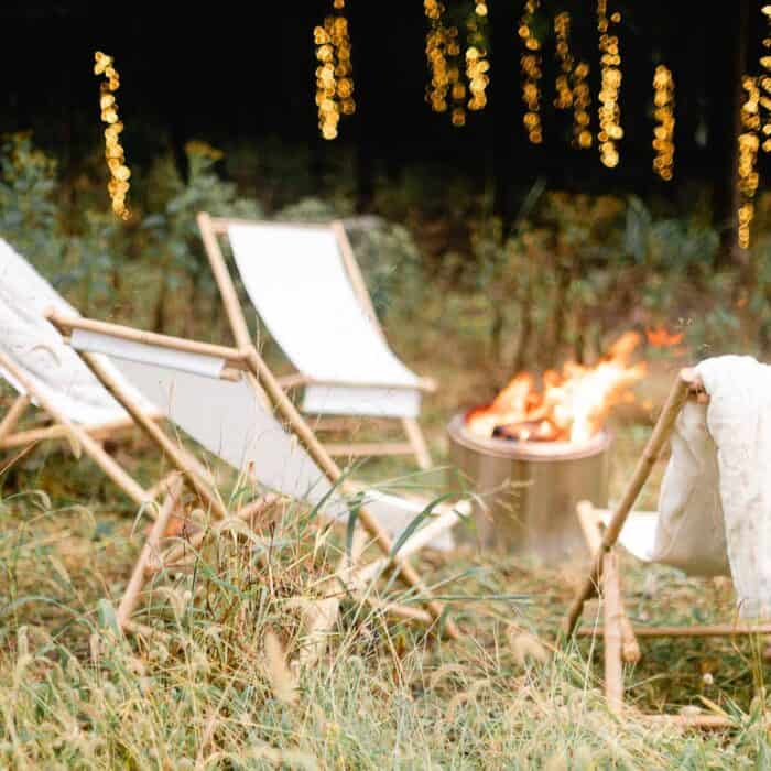 A roaring fire in a solo stove with twinkling outdoor Christmas lights for the holidays.