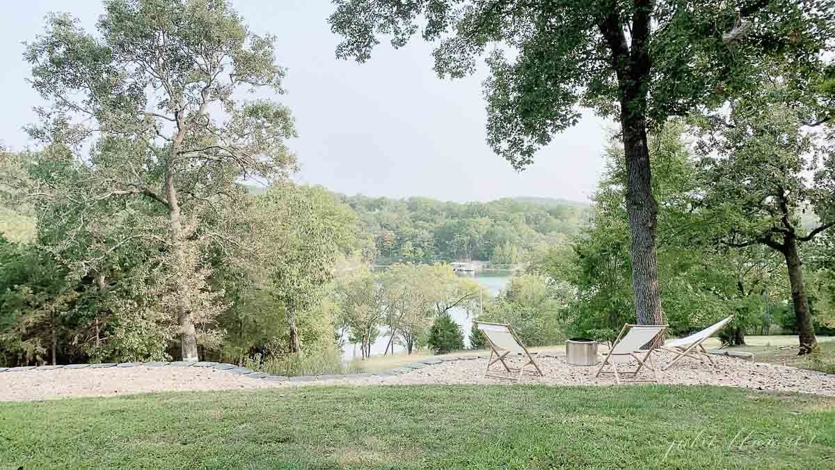 a lake view through trees, with a solo stove and wooden sling chairs surrounding.