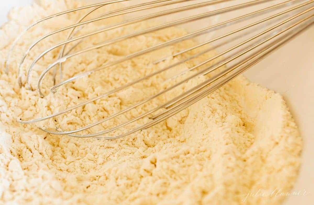 A whisk in a bowl of dry ingredients for cookie dough.