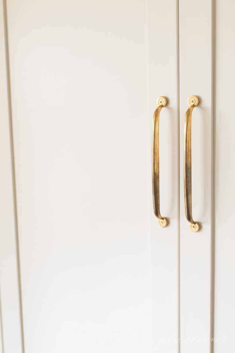 Brass cabinet knob pulls on a white refrigerator cabinet.