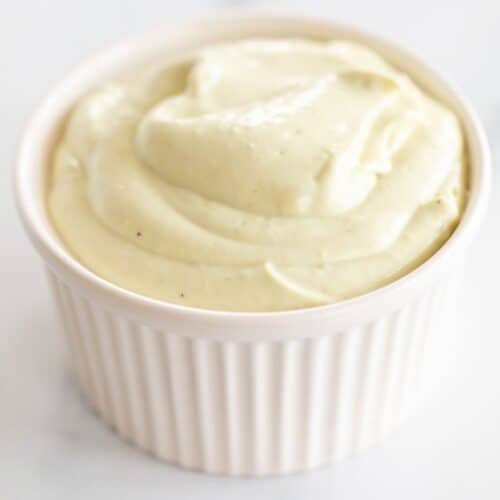 A white ramekin filled with avocado mayo on a marble surface.