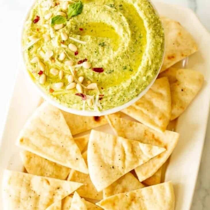 Basil Pesto Hummus and pita chips on a platter.