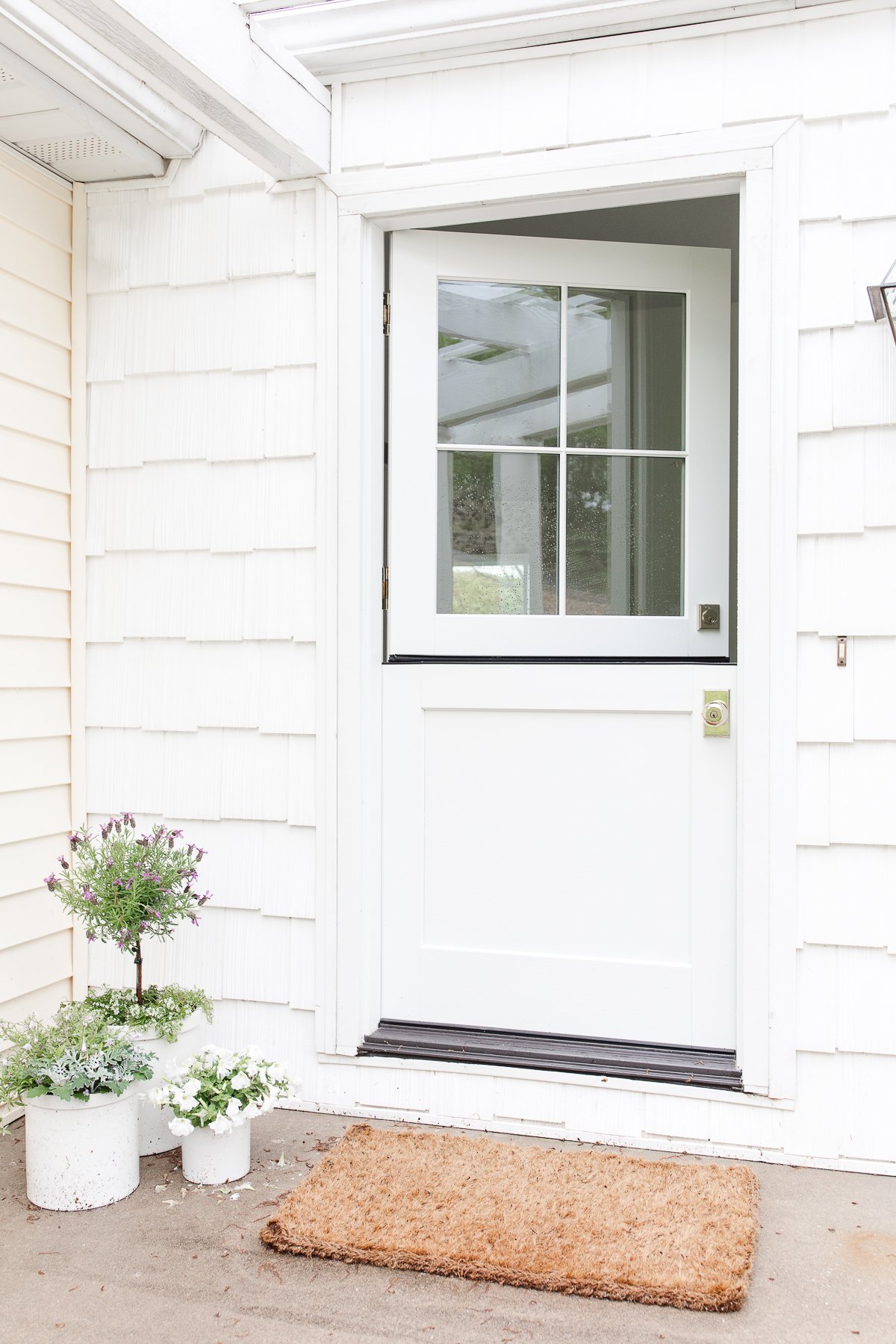 A white Dutch door on a white shingled cottage.