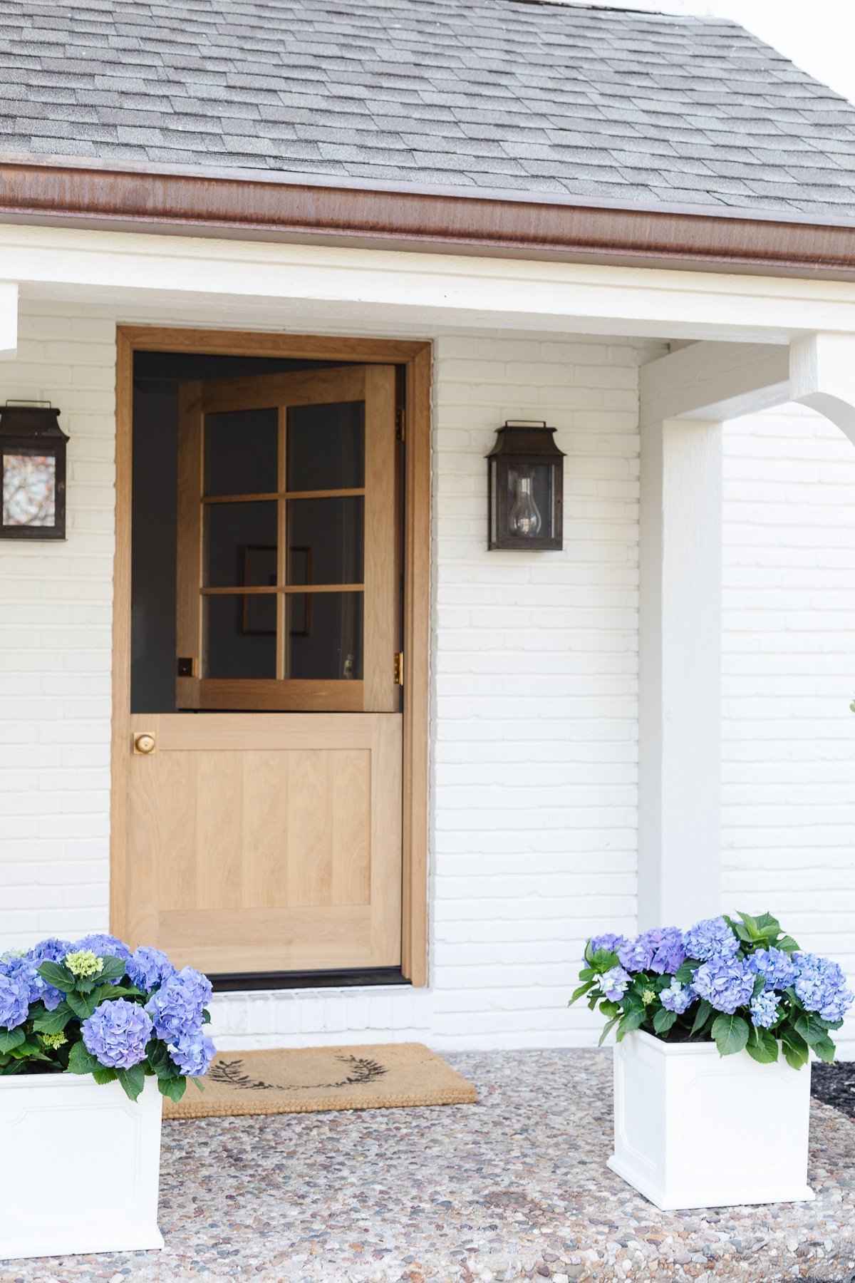 A wood Dutch door on a white brick home.