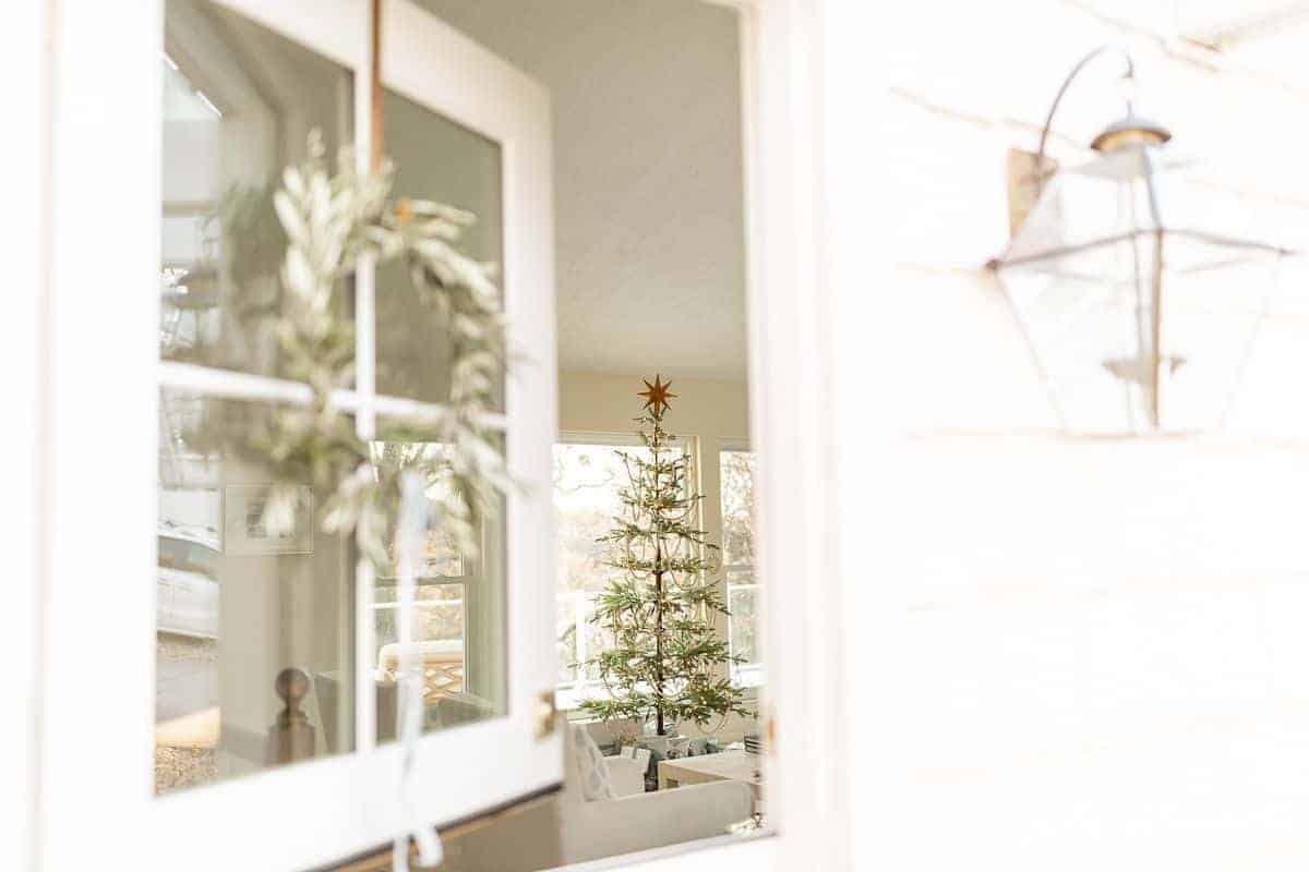 A white exterior dutch door, open looking into a living room with a christmas tree.