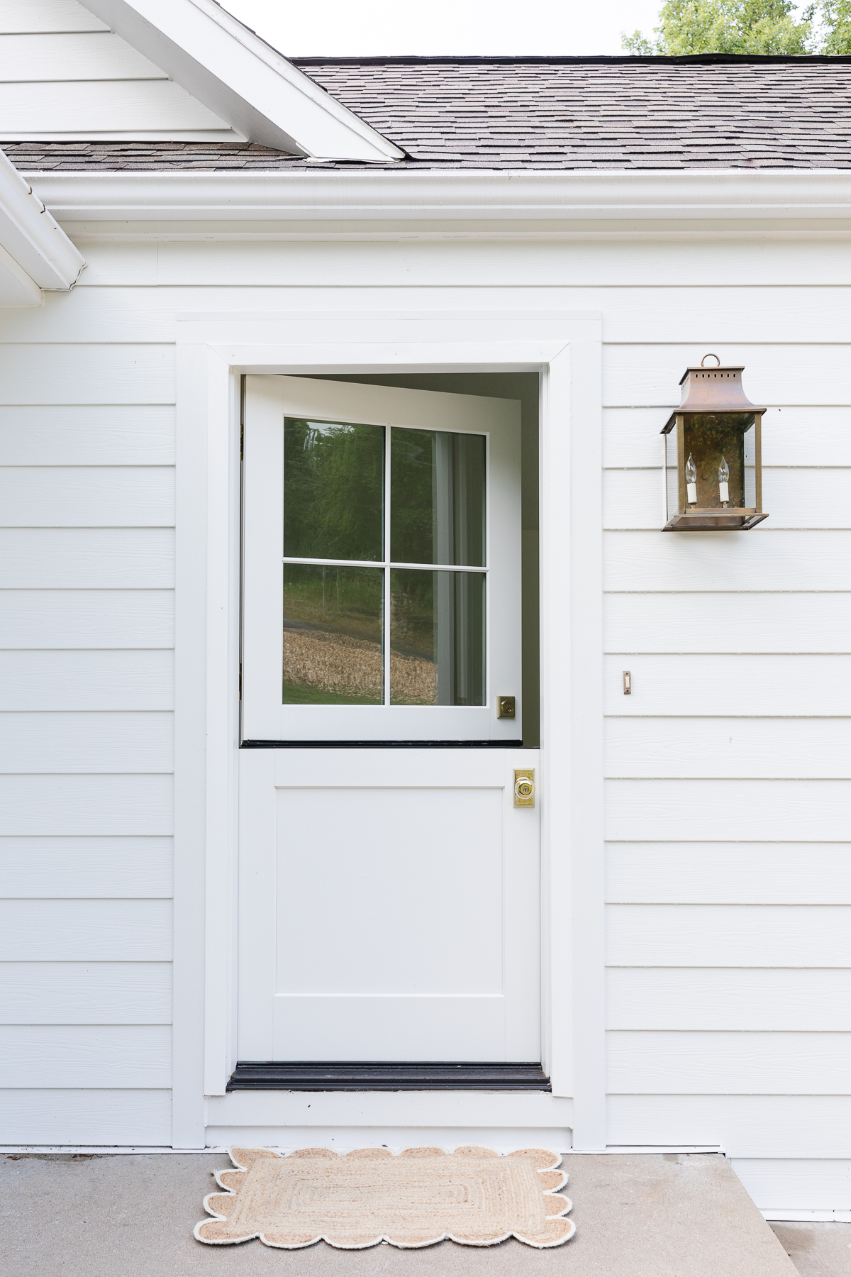 A white Dutch door on a white shingled cottage.