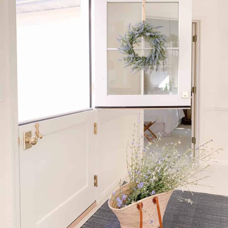 A white living room with large windows and a dutch door with the top half open.