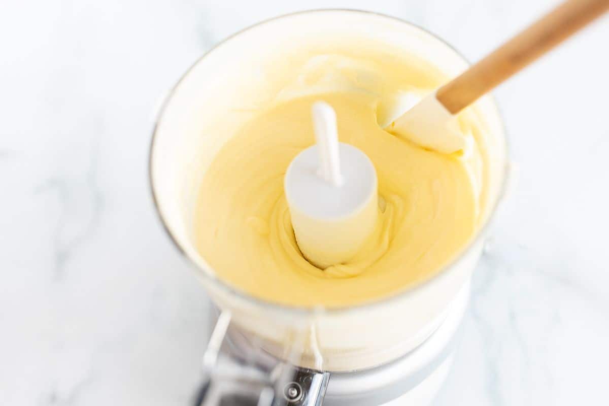A small food processor filled with the ingredients for homemade mayo.