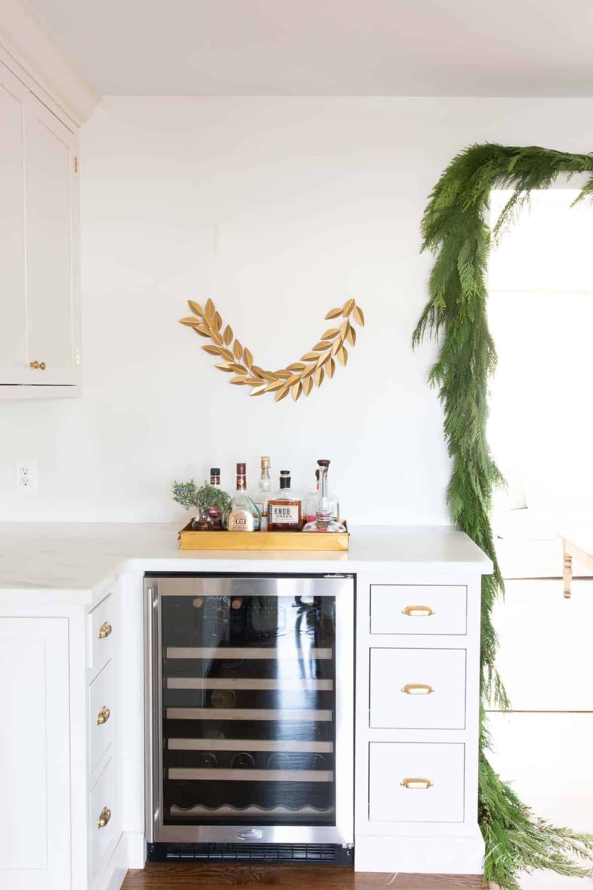 A kitchen with inset cabinets and a wine fridge, Christmas greenery hanging.