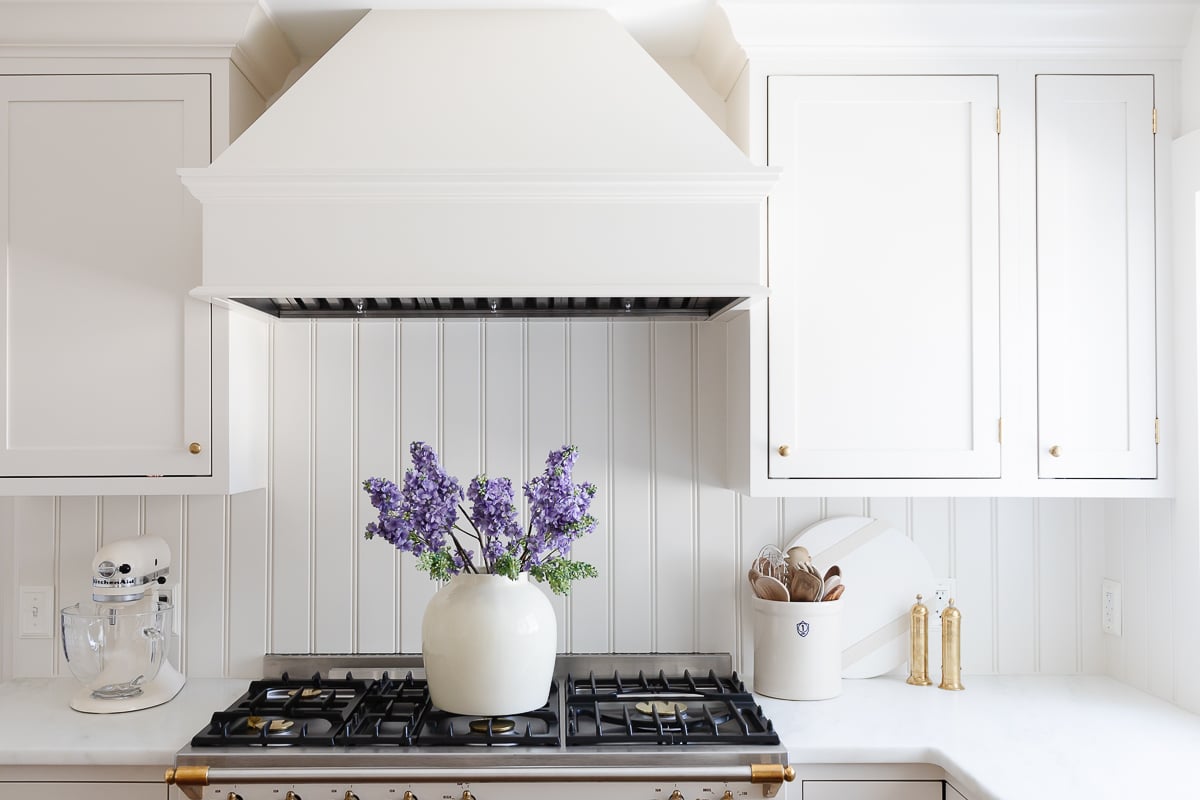 A cream kitchen with inset cabinets and a wood island. 