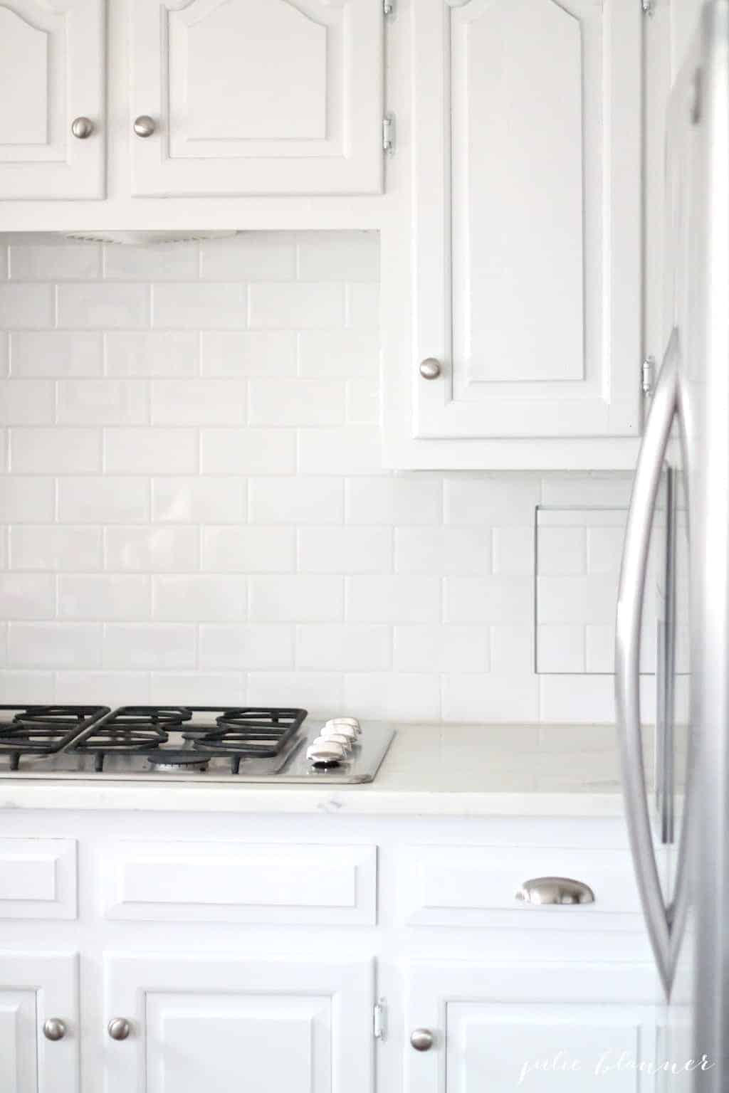 A white kitchen with white subway tile backsplash.