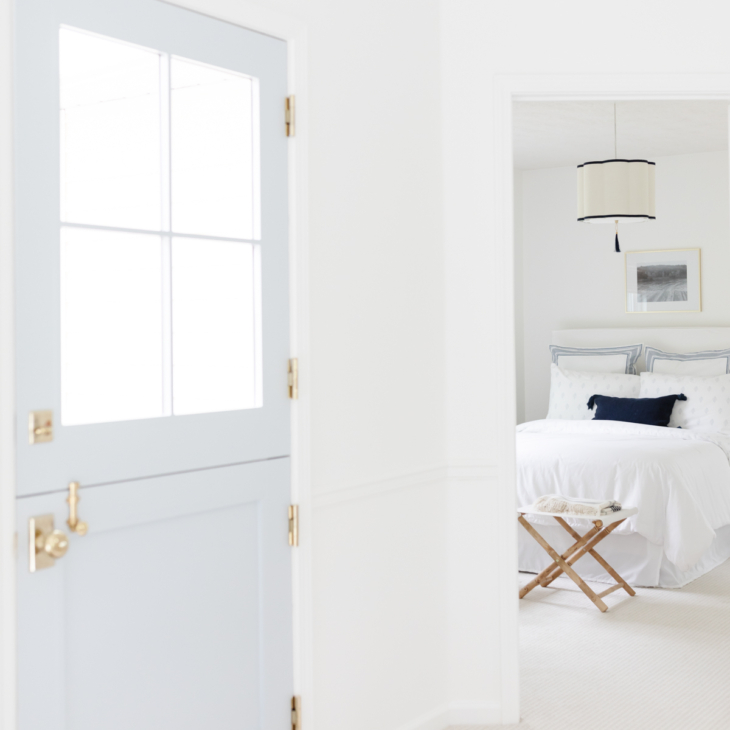 A blue Dutch door with a simple guest bedroom beyond.
