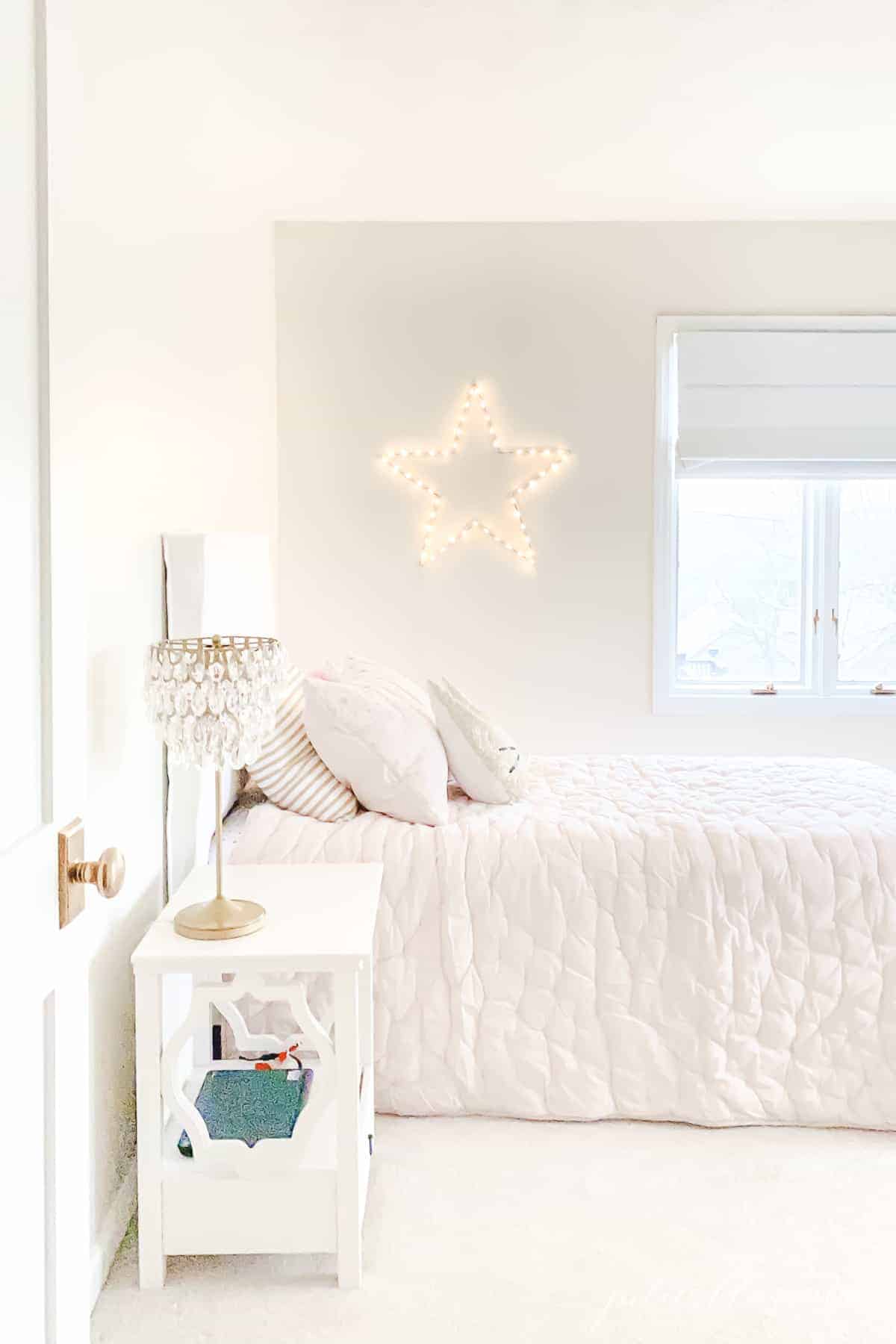 cream bedroom with pink quilt chandelier lamp and star light