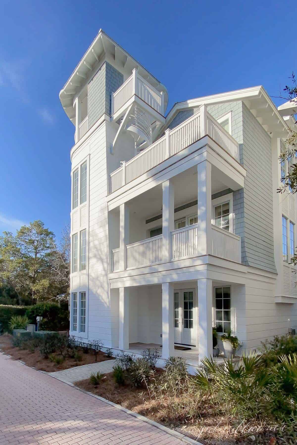 A charming three story white beach house with a white front porch in Seaside Florida