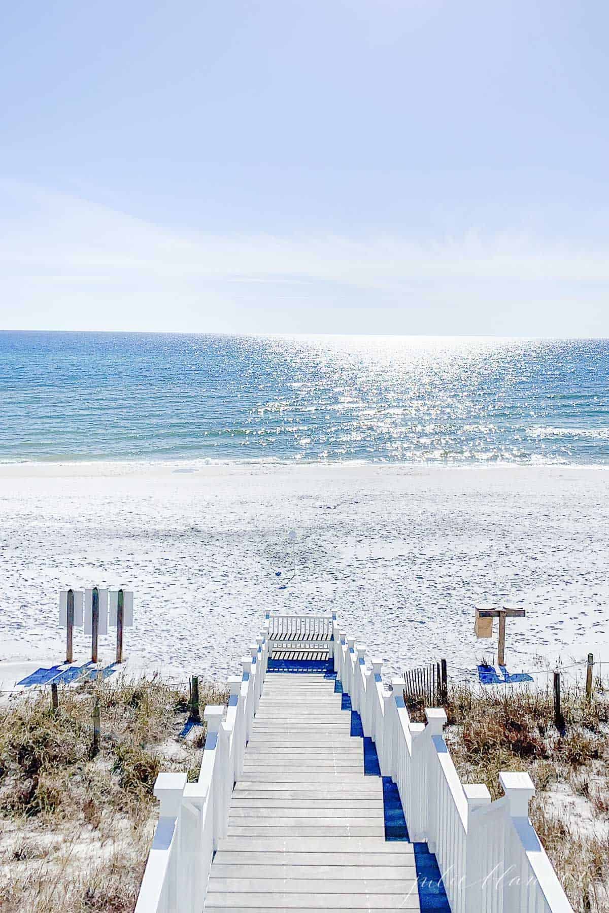 A sandy beach scene with stairs in foreground, then sand and beach.