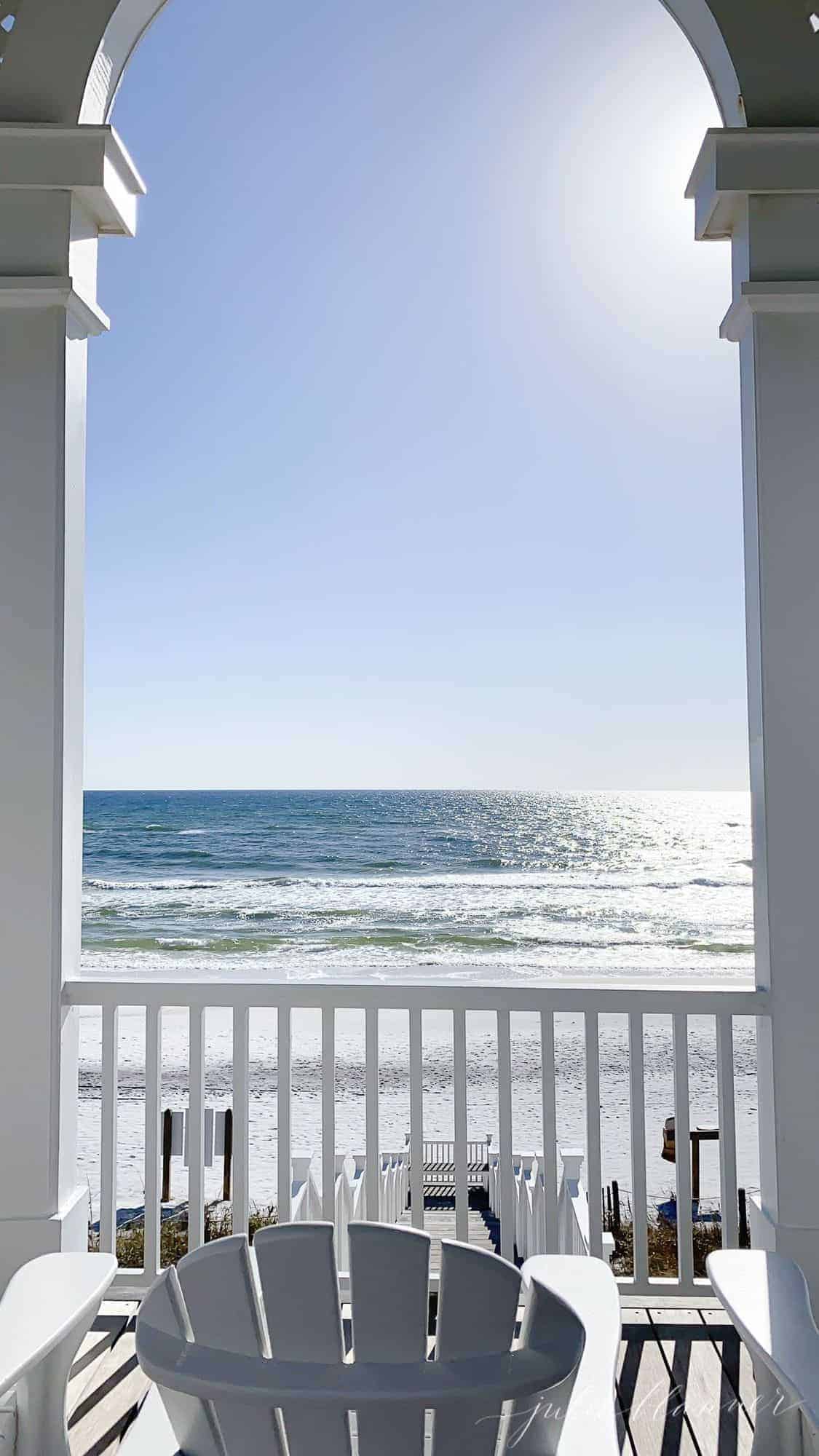 A beach scene looking through a pavilion with seating.