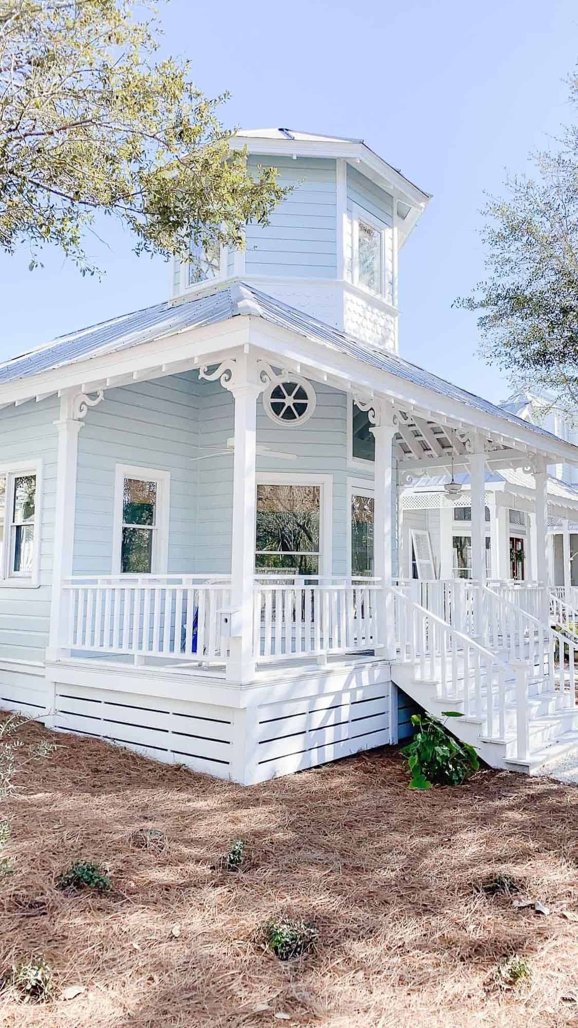 A charming pale blue beach house with a white front porch in Seaside Florida
