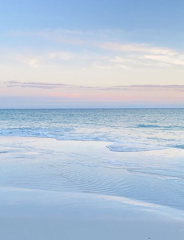 A blue and pale pink beach sunset scene