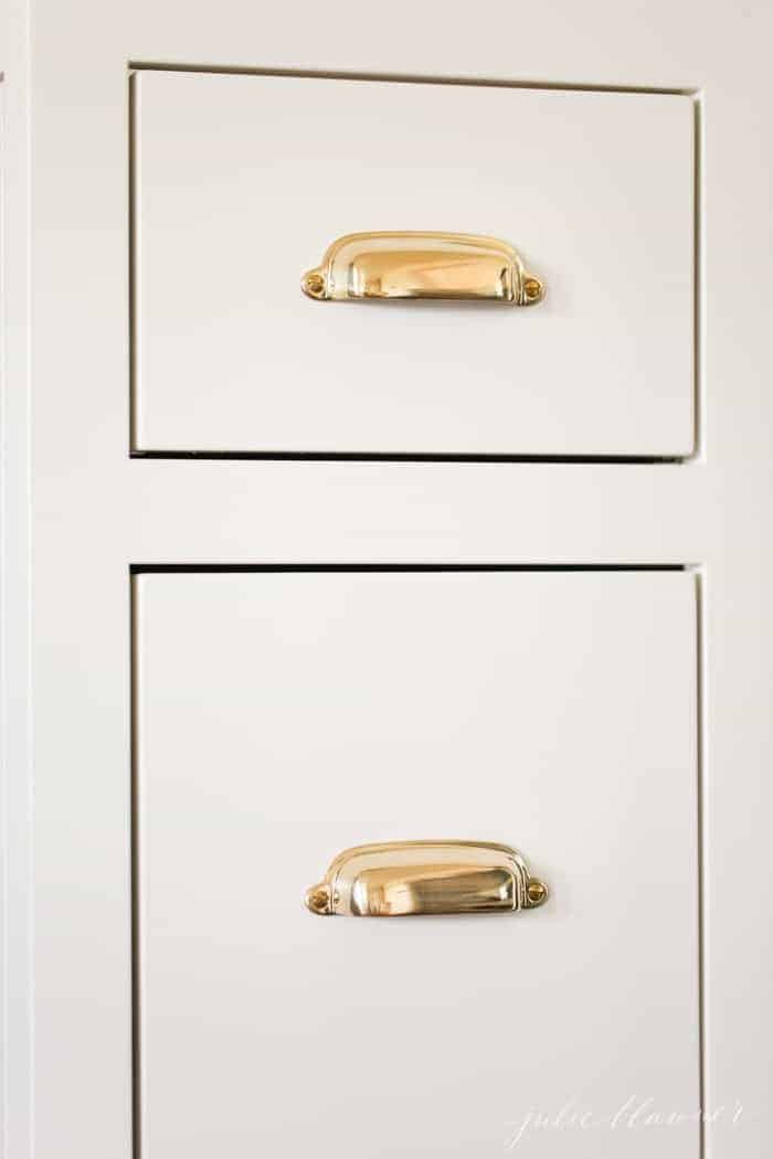 Brass cabinet pulls on cream inset kitchen cabinets.