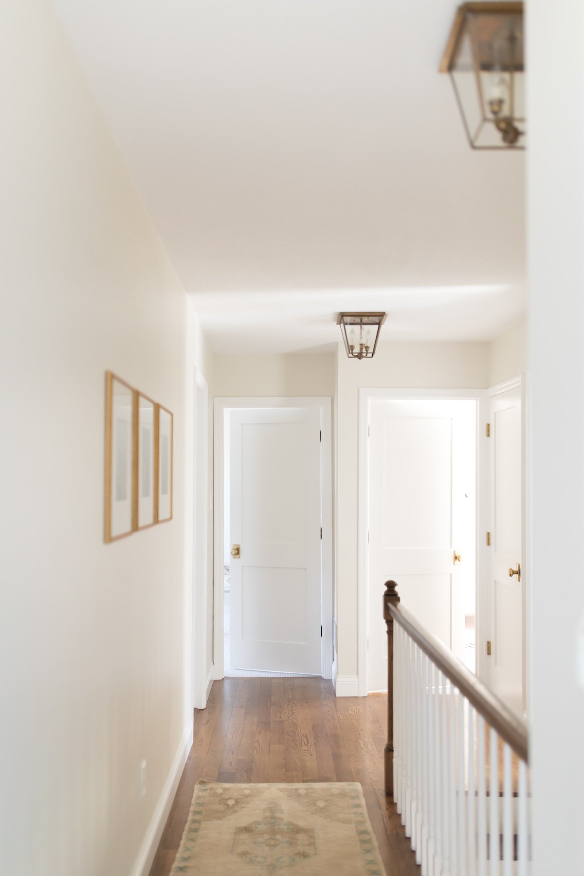 A hallway in a home with white walls and shaker style doors.