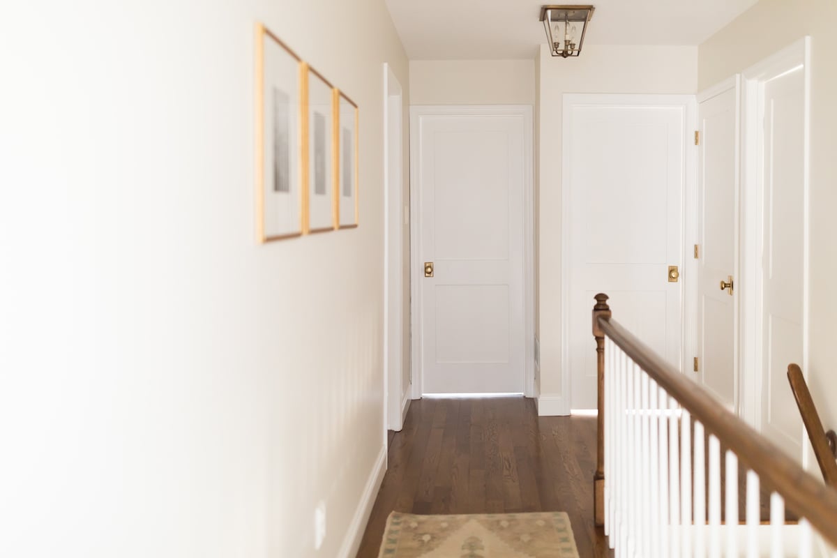 A hallway with shaker-style white doors and a rug.