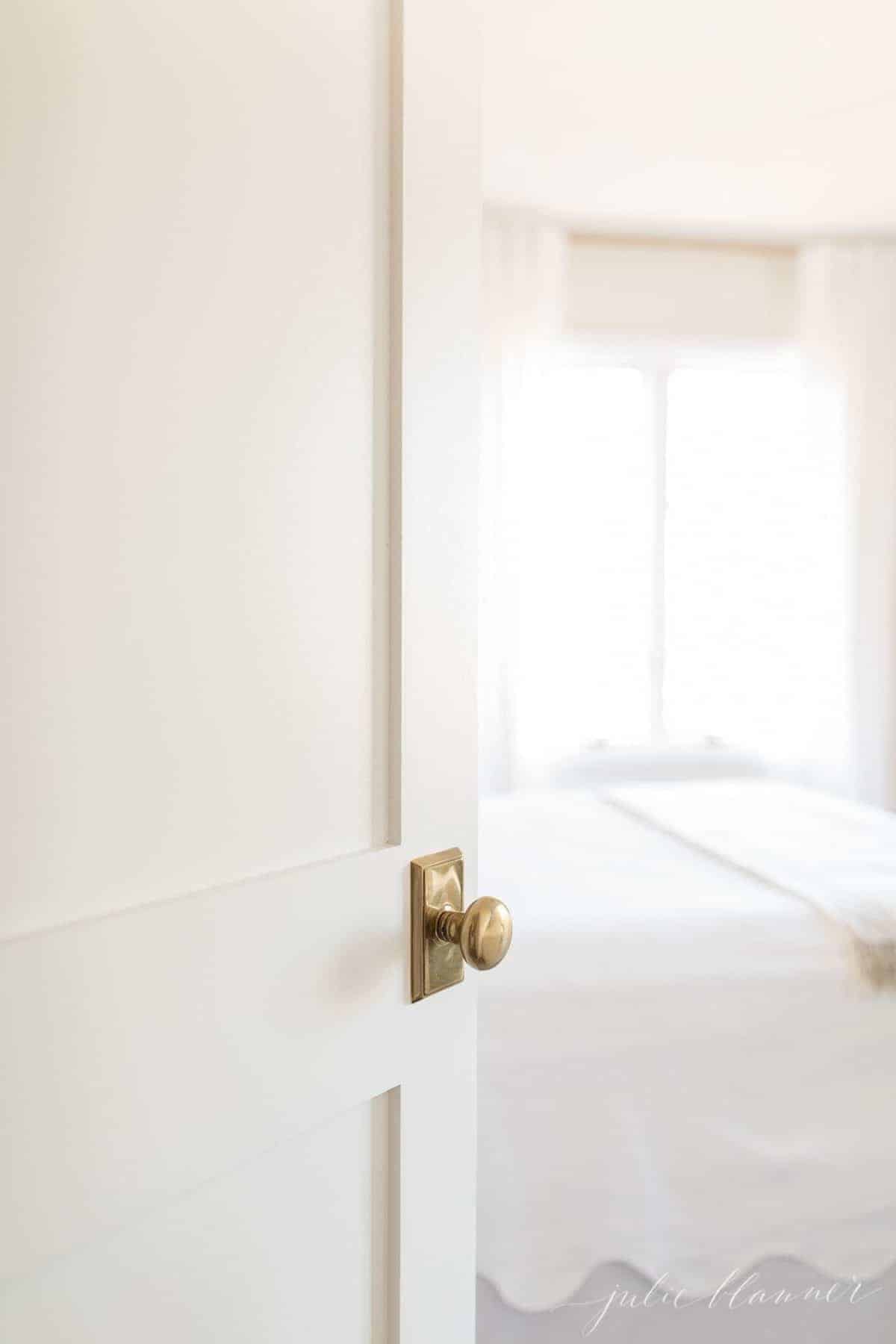 A white Shaker style door with a brass doorknob, opening into a bathroom.