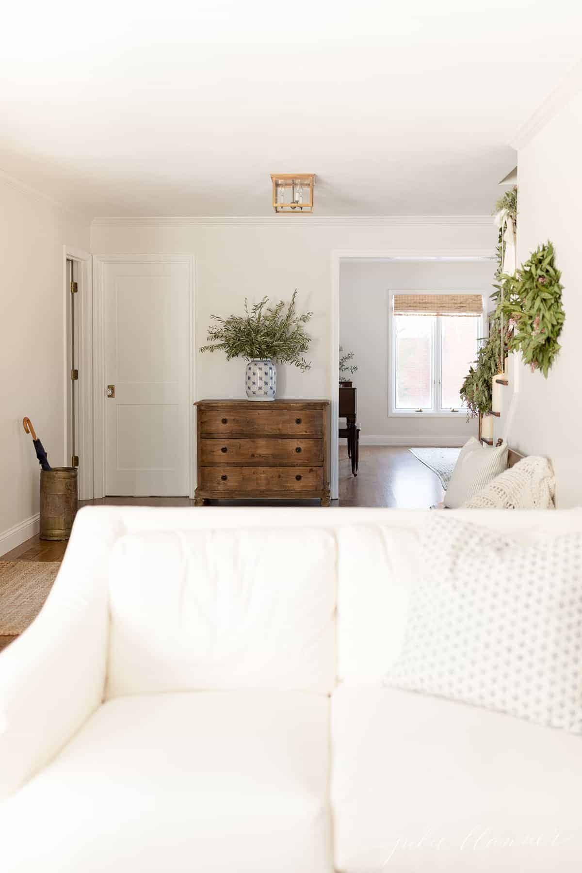 A living room with a white sofa and a Shaker interior door leading to a bathroom.