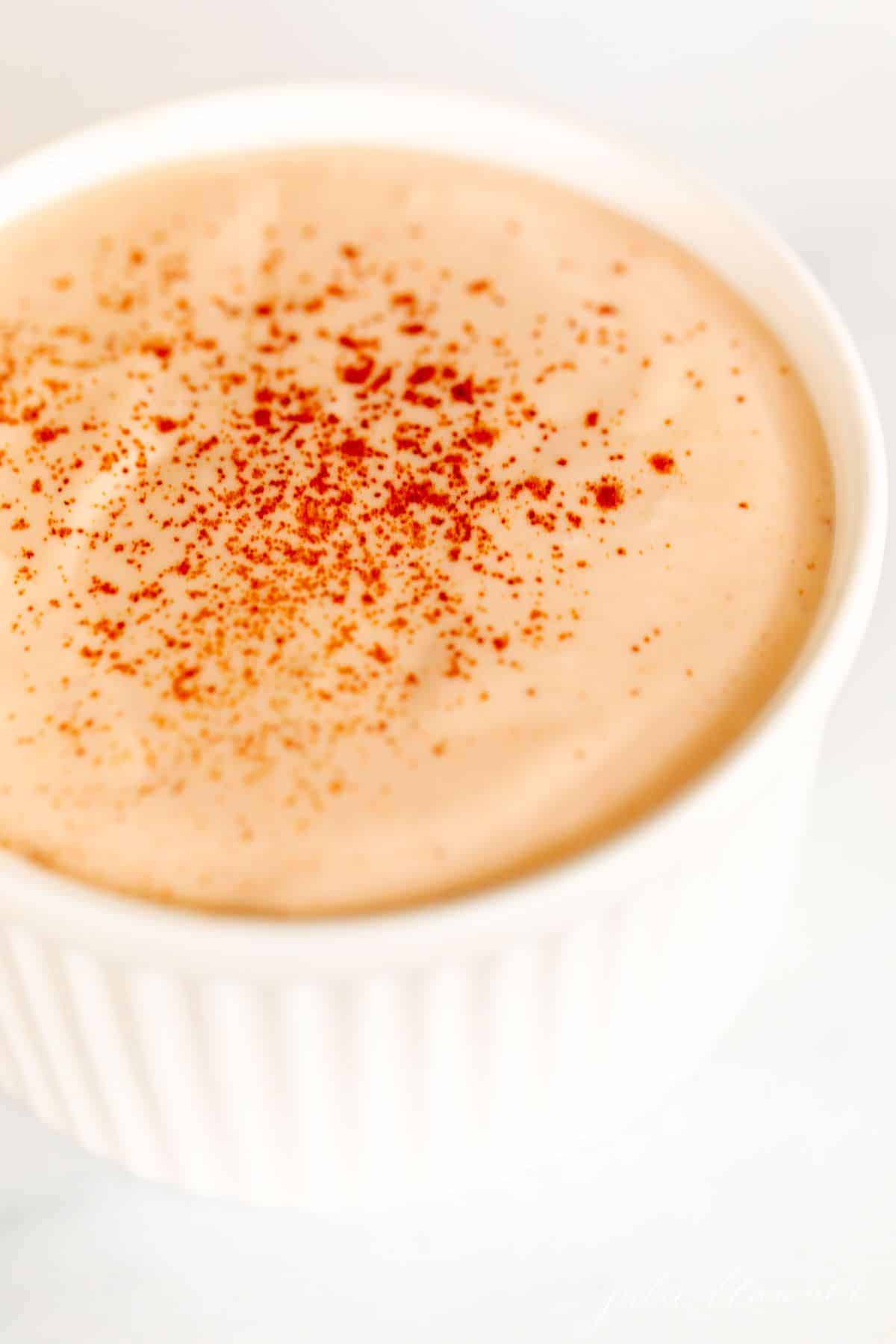 A white bowl full of homemamde sriracha mayonnaise on a white background.