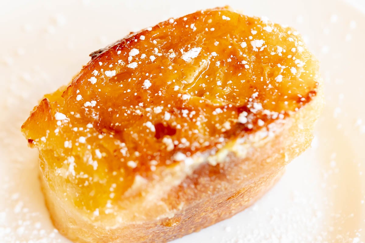 a slice of creme brulee french toast on a white plate. 