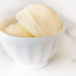 A small white bowl full of sweet butter on a marble counter top.