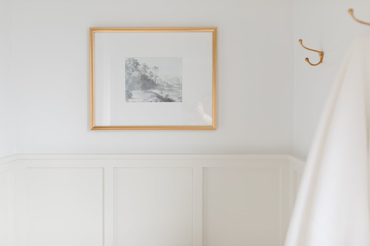 A white bathroom adorned with a stunning gold framed picture sourced from Studio McGee.